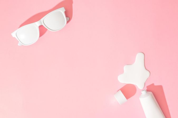 Sunglasses and sunscreen on pastel pink background