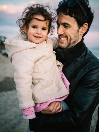 father holding little daughter at the beach