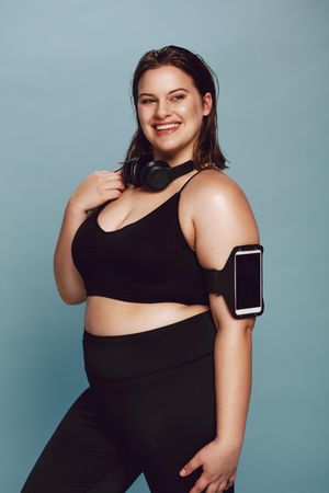 Plus size young lady in sportswear and smiling at camera