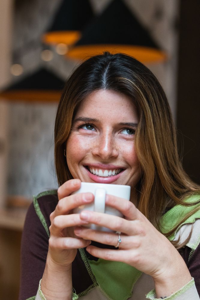 Contemplative cheerful woman with cup of coffee in cafe