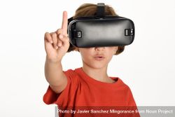 Little girl looking in VR glasses and gesturing with finger pointing up bej7P0