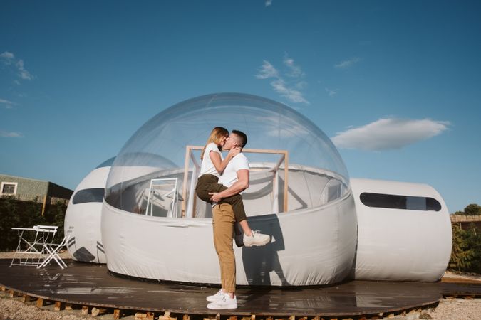 Affectionate couple kissing near bubble hotel