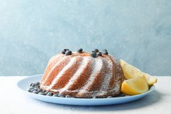 Cake with powder sugar and blueberry on blue background, space for text