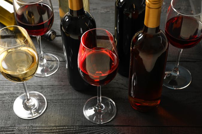 Composition with bottles and glasses of different wine on wooden background