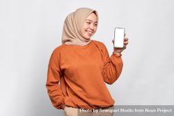 Muslim woman smiling at smart phone’s mock up screen 4OANa0