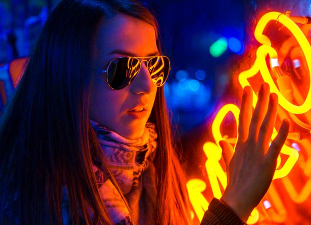 Stylish young woman near illuminated board