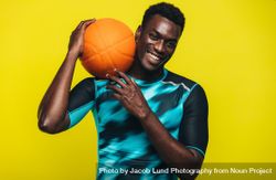 Young basketball player against yellow background 4mPao5
