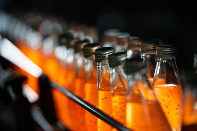 Side view of orange drink bottles in a line