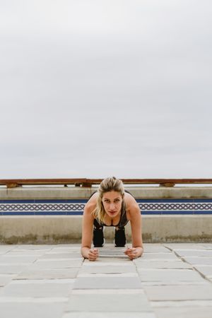 Sportswoman practicing plank on lonely sandy seashore