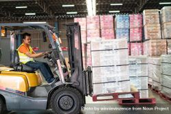Man driving forklift iand moving merchandise in distribution center 5k9AAb