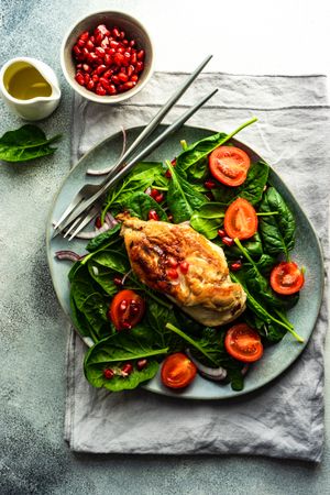 Fresh organic salad with chicken, spinach, tomato and pomegranate seeds