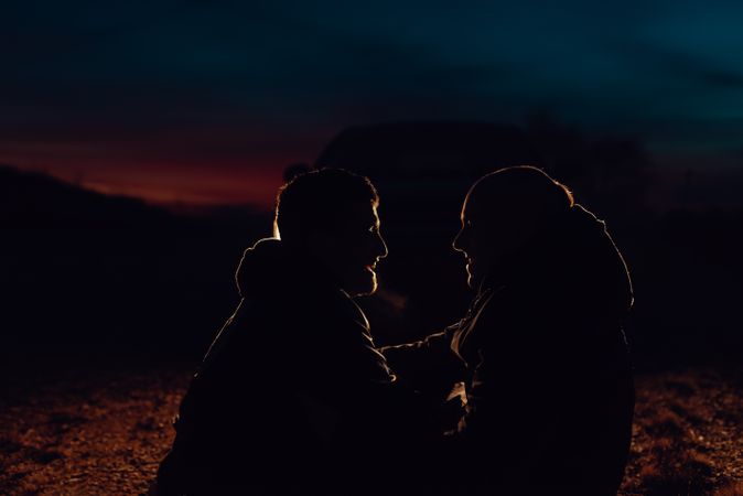 Men hugging and sitting on ground on field at night