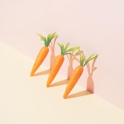 Row of carrots on pastel yellow background