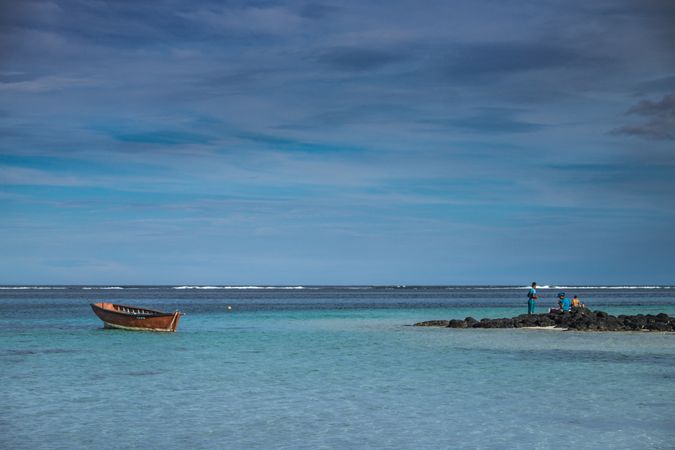 Red boat anchored in tropical lagoon in Mauritius near volcanic rock