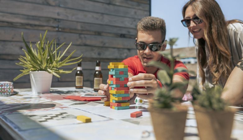 Man and woman playing with tower wooden stacking on terrace