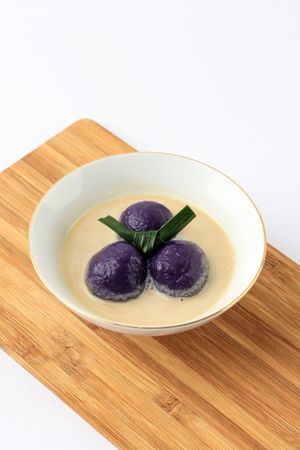 Dessert of purple sweet potato balls covered in coconut milk sauce