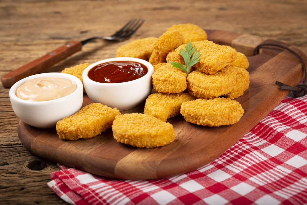 Fried chicken nuggets with ketchp and rose sauce.