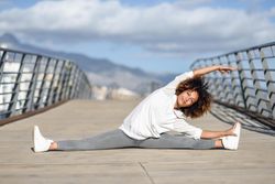Woman leaning to right side in splits on bridge with head resting on hands