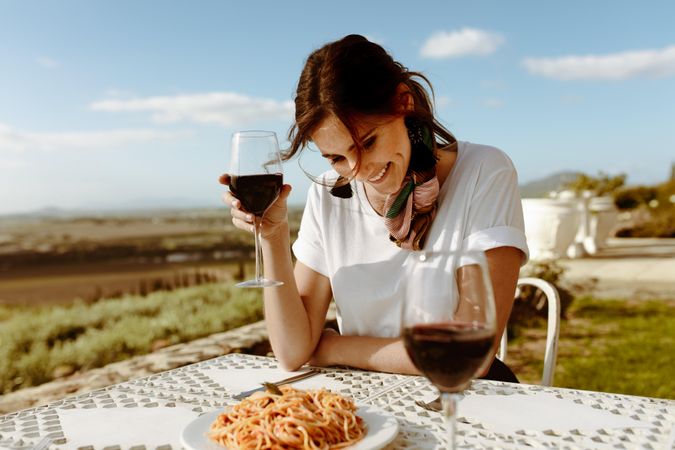 Smiling woman on a wine date sitting with a glass of red wine in hand