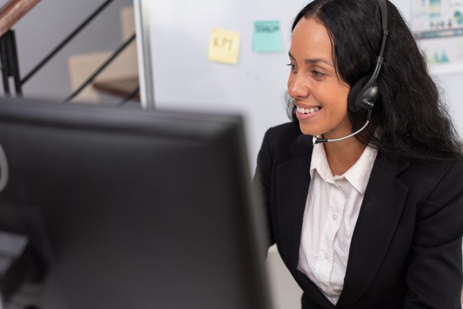 Hispanic employee working at desk to support customers in the office