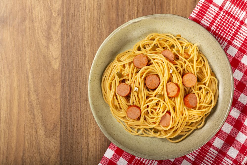 spaghetti pasta with sliced sausages and tomato sauce.