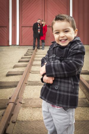 Boy at Train Depot with Parents Smiling Behind
