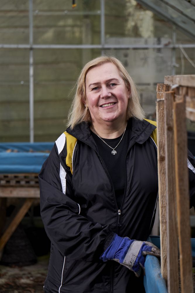 Woman smiling and looking at camera inside greenhouse