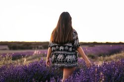 Back view of a woman walking through a lavender field.