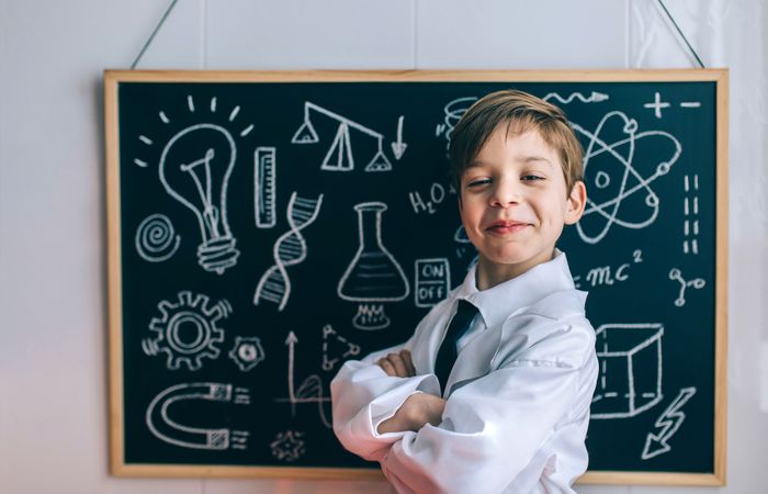 Smiling kid looking at camera in front of chalkboard