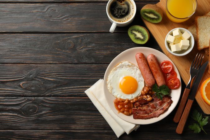 Top view of fried breakfast with kiwi, coffee and juice on table, copy space