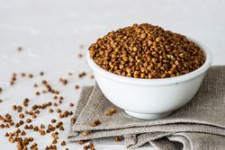 Organic raw buckwheat seeds in a bowl on wooden table with copy space