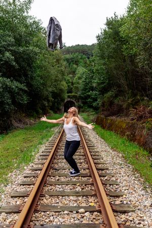 Woman walking along railway though greenery part of road