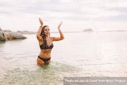 Smiling woman in bikini splashing water and enjoying the ocean water 0y6Qq5