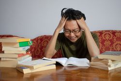 Asian young male reading book with frustrated gesture