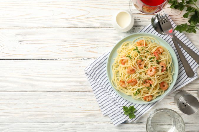 Composition with plate of tasty pasta with shrimps on wooden background