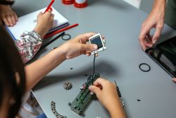 Female student connecting solar panel to electrical circuit in a robotics class