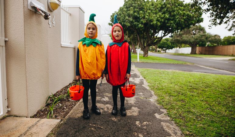 Children in pumpkin costumes trick-or-treating on Halloween