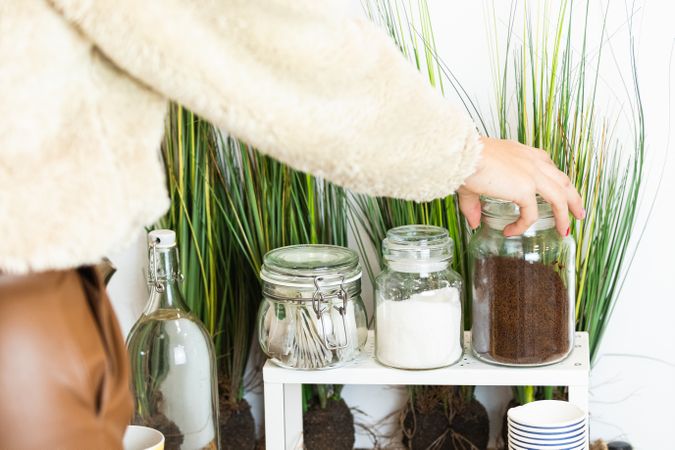 Unrecognizable person hand picking up a glass jar full of coffee