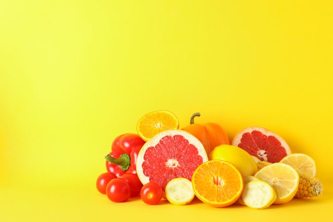 Different vegetables and fruits on yellow background, copy space