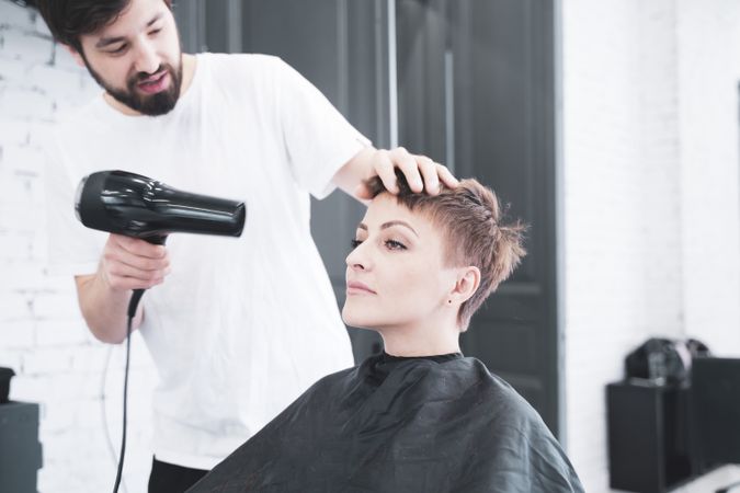Hairdresser drying hair to woman