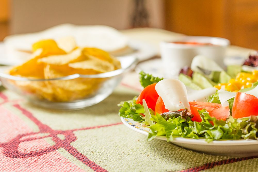 Traditional mexican food with a plate of fresh salad, tortillas, nachos and a bowl of spicy sauce