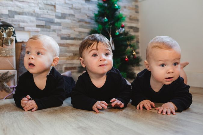 Happy babies near Christmas tree and gifts