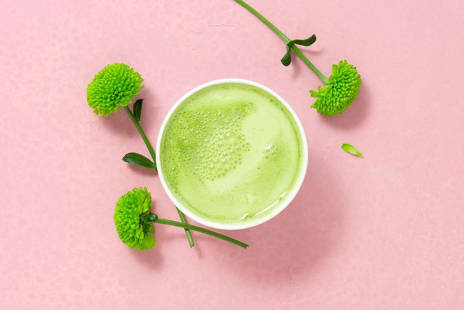 Top view of green tea on pink table with flower