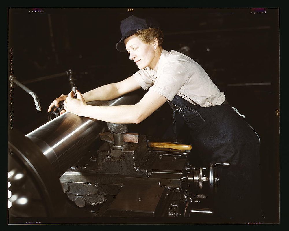 Milwaukee, WI, USA - 1943: Woman leaning over gun manufacturing machinery