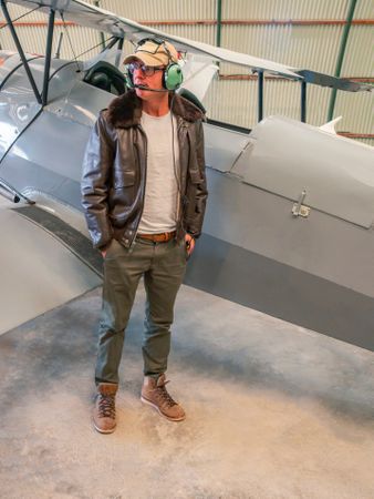 Confident pilot beside retro plane in hangar