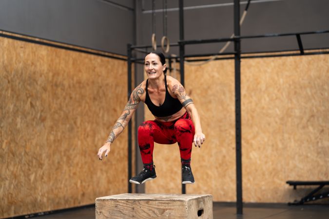 Woman jumping onto a box in a gym