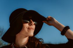 Dreaming stylish woman in sunglasses and hat