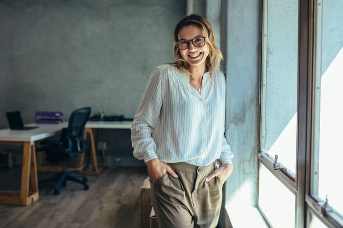 Successful female entrepreneur standing in office with hands in pocket
