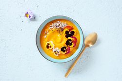 Top view of creamy pumpkin soup with edible flowers
