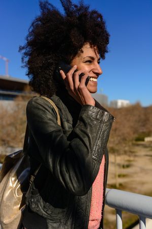 Woman with afro hair looking at her phone while walking.